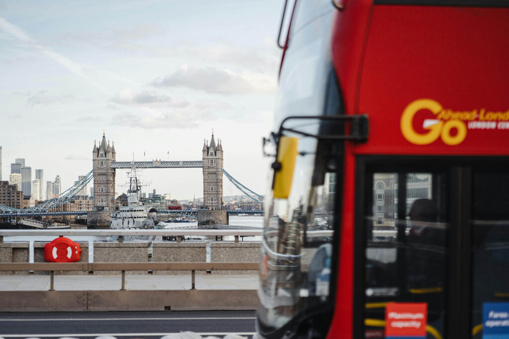 A photo of a red London bus in the foreground with Tower Bridge in the background