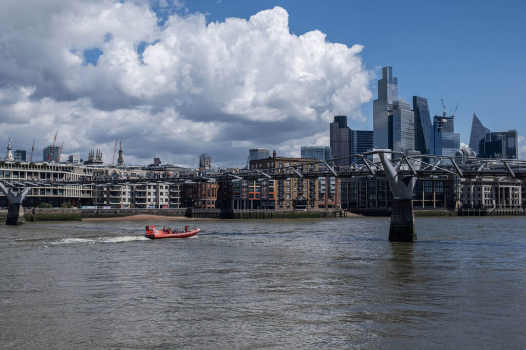 Photo of a RIB boat doing a cruise on the Thames river in front of the City of London