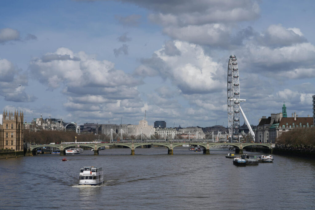 Photo of a boat on the Thames river doing a cruise with the London Eye in the background.