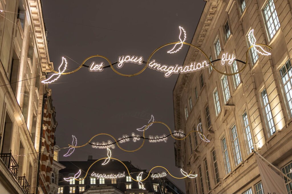 A photo of Christmas lights on Regent Street that say 'let your imagination fly' from 2024.